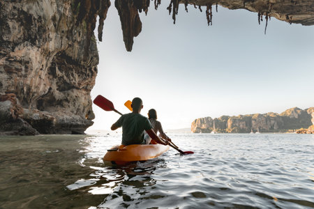 Young couple walks on kayak at tropical sea bay between cliffs. Kayaking or canoeing conceptの写真素材