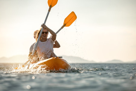 Young couple walks on sea kayak or canoe at calm sunset seaの写真素材