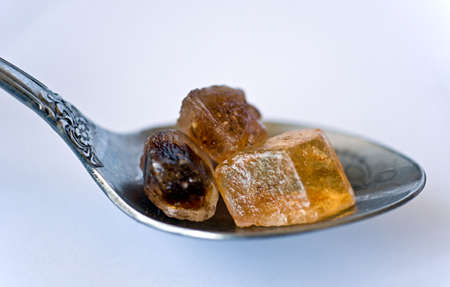 Spoon with cane sugar cubes on white の写真素材