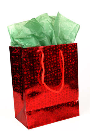 Red shiny Christmas gift bag with green tissue on white.の写真素材