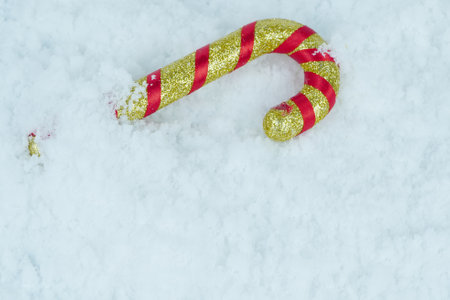 Gold red glittered candy canes on the white snow. Copy spaceの写真素材