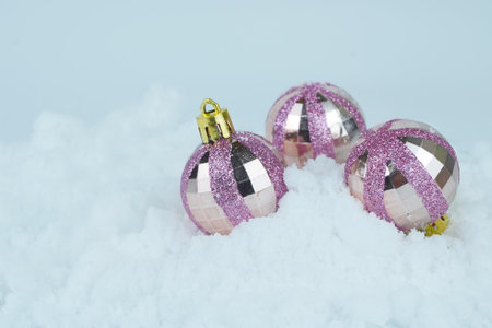Pink Glittered Christmas baubles on he snow. Close up photo. Defocused and blurred background.の写真素材