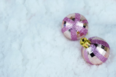 Pink Glittered Christmas baubles on he snow. Close up photo. Defocused and blurred background.の写真素材