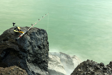 Fishing rod is left on the rock at the Marina Beach Semarang. Indonesia.の写真素材