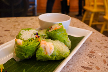 Fresh vietnamese spring rolls with peanut butter sauce for dipping served on the marble table at the restaurant.の写真素材