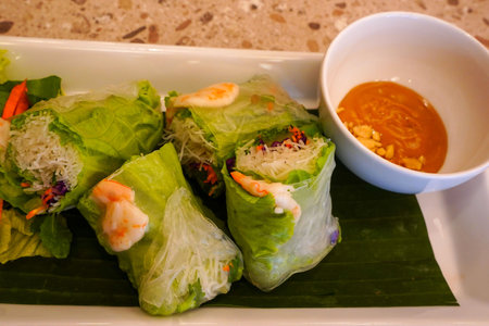Fresh vietnamese spring rolls with peanut butter sauce for dipping served on the marble table at the restaurant.の写真素材