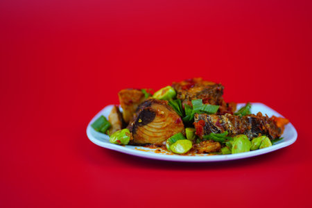 Indonesian food, Cakalang Balado or chilli stir fry skipjack tuna with bitter beans. Isolated on red background.の写真素材