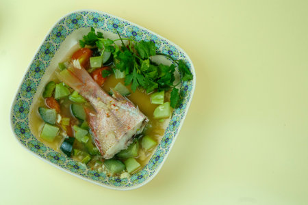 Red snapper soup with bitter melon, cucumber and chayote and varied herbs served in plate. Shot in studio.の写真素材