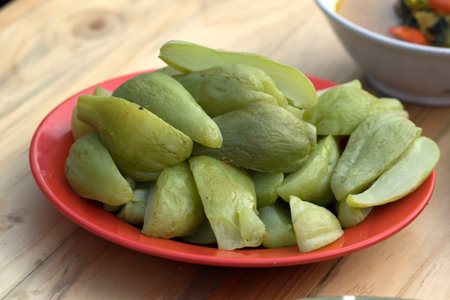 Cut boiled chayote served on a red plate. Food Photography.