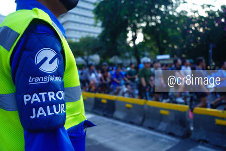 July 23, 2023. Jakarta, Indonesia. An attentive officer on duty, skillfully orchestrating traffic flow and ensuring safety during Jakarta's lively carfree day event. With a firm grasp on crowd management and road regulations, this dedicated professional tのeditorial素材