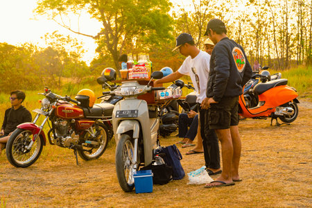 August 08, 2023. Surabaya, Indonesia. Barista on bike selling drinks during sunset in a hill forest. Street Photographyのeditorial素材