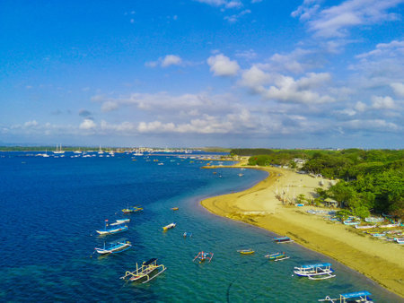 A serene oasis in the heart of Sanur, Cemara Beach is a picturesque stretch of white sand and crystal clear waters. Swaying palm trees frame the coastline and the moored traditional boats.の写真素材