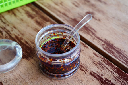 Chili oil in a glass jar on a wooden table. Selective focus.の写真素材