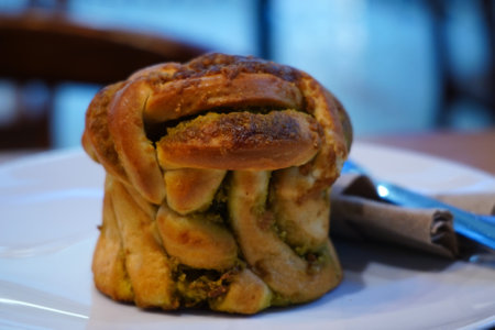 A close-up of a flaky croissant on a white plate with a knife and napkin. Food Photography