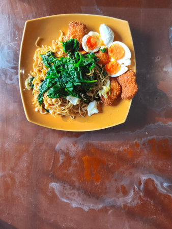 A plate of instant noodles topped with spinach, hard-boiled eggs, and fried fish cakes.の写真素材