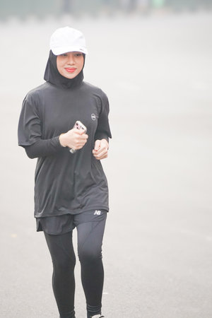 young fitness woman running in city at early morning with foggy background