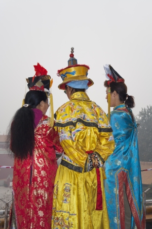 Three women in traditional chinese clothing greet tourists to the Forbidden City in Beijingのeditorial素材