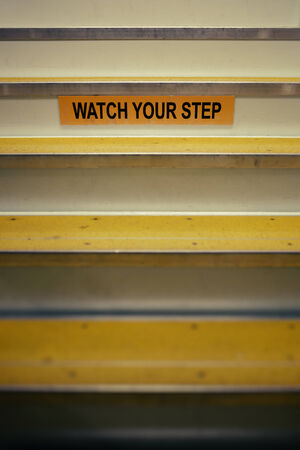 Watch your step sign on stairs leading up