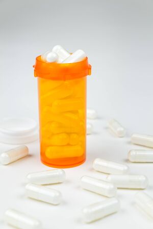 A prescription medication bottle filled to the top with white pillsの写真素材