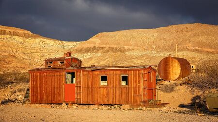 An abandoned red caboose in warm light in the ghost town of Rhyolite near Death Valley National Parkの写真素材