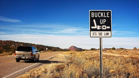 Car passes a Buckle Up It's The Law sign along an Arizona highwayの写真素材