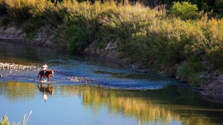 Mexican man on horse rides through the Rio Grande river Big Bend National Parkのeditorial素材