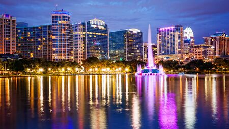 Orlando, Florida city skyline and water fountain at night in Lake Eola Park, building logos blurred for commercial use)の写真素材