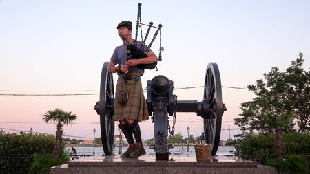 Man in kilt playing bagpipes next to cannon at sunset at Jackson Square in the French Quarter of New Orleans, Louisianaのeditorial素材