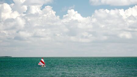 Dreamy sailboat with red and white striped sail in the tropical ocean of the Florida Keysの写真素材