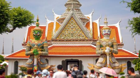Twin giants stand guard at the entrance to Wat Arun in Bangkok, Thailand (people blurred for commercial use)の写真素材
