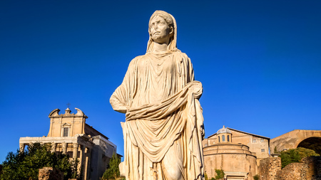 Ancient and weathered statue of a woman with the Roman Forum ruins in background in Rome, Italyの写真素材