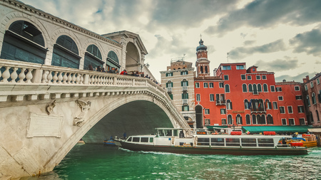 Vaporetto passes underneath Rialto Bridge. The bridge is oldest bridge crossing the Grand Canal  in Venice, Italyの写真素材