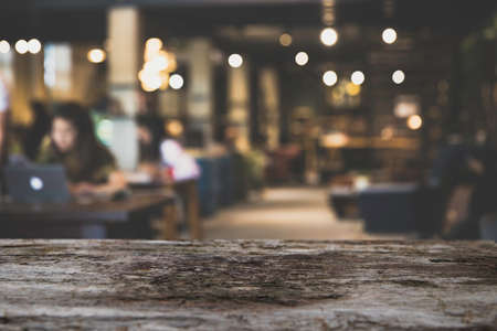 Old wood Table top Counter with blurred of coffee shop or modern library . Abstract, freelancer working on laptop in cafe with a cup of coffee.の写真素材