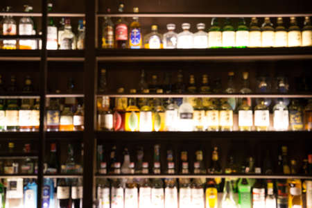 blur bottle of alcohol drink at club pub or bar in dark party night backgroundの写真素材