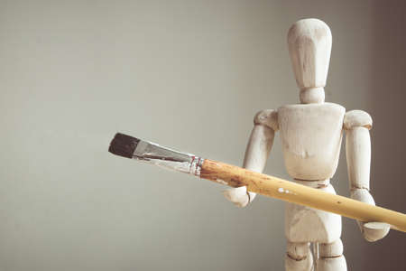 Painter's wooden model holding paintbrushes with copy space.の写真素材