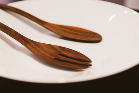 Selective focus Empty plate with wooden folk and spoon. Vintage filter. Ready to eat concept.の写真素材