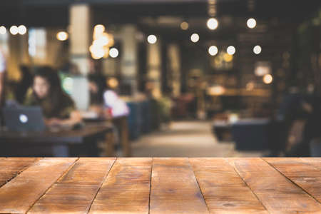 Wood Table top Counter with blurred of coffee shop or modern library . Abstract, freelancer working on laptop in cafe with a cup of coffee.の写真素材