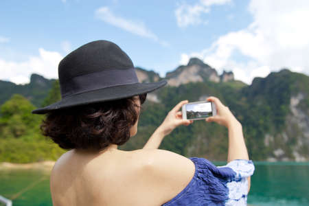 Back view of woman  Wearing stylish blue dress and stylish hat.   taking pictures of in Khao Sok lake or sea. Travel conceptの写真素材