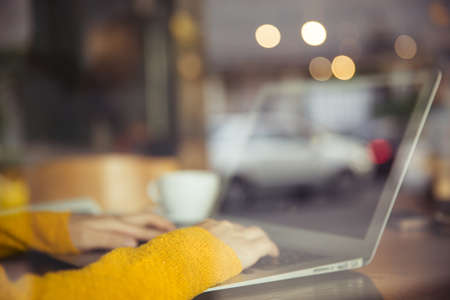 businesswoman using computer in newyork cafe. Close-up of female hands using laptop at caafe, woman's hands typing on laptop keyboard in interior. side view ofの写真素材