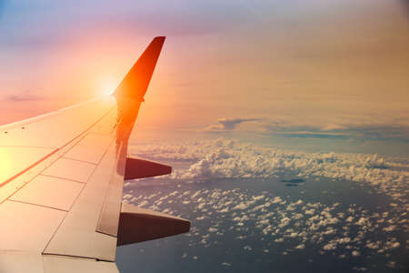 View on the sunset and airplane wing from the inside.の写真素材