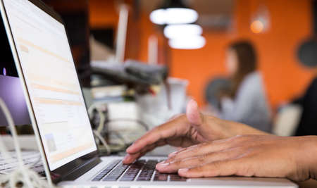 Closeup selective focus image of an Asian business man working and typing on laptop keyboard in officeの写真素材