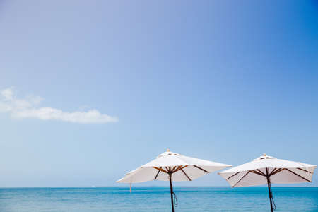 Vintage white umbrella with the blue sky and blue water. Summer style vacation. Background concept.の写真素材