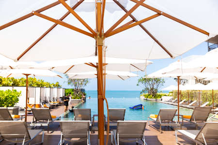 Peopple relaxing and enjoy a luxury infinity swimming pool in the beach hotel resort with the pool...