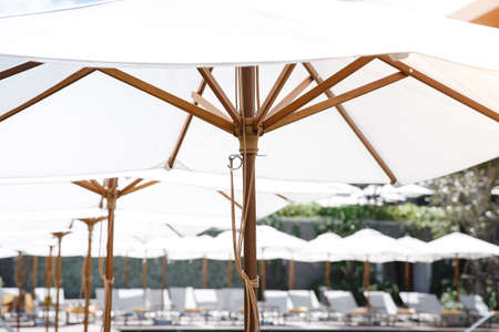 White vintage ambrella at the pool side with the comfortable bed cushion in the hotel resort.の写真素材