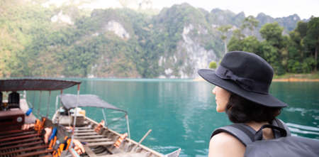 Traveler woman wearing big black hat and backpack looking at destinations sea beach. Summer holiday and vacation tripの写真素材