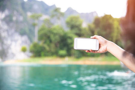 White screen showing on the smartphone with tropical island and mountain background.の写真素材