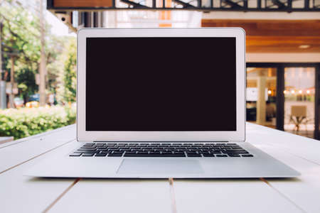 Modern computer,laptop with blank screen on white table with defocused of cafe,restaurant background.の写真素材