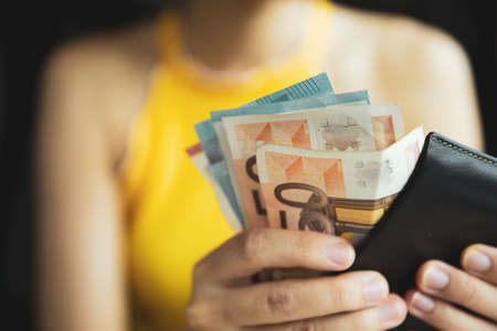 A female hand piking up or counting money in the wallet. Budget for travelling or purchacing.の写真素材