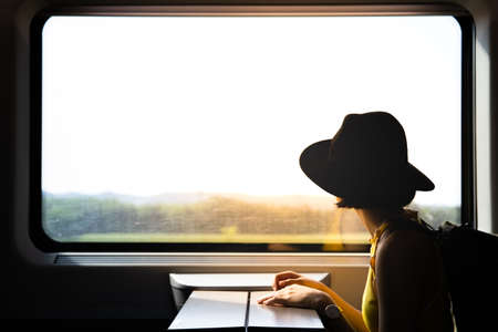 A beautiful hipster asian woman travelling on the train. Sitting on the black leather cozy comfort seat in the business class boky of the train in Europe. Tourist travel concept.の写真素材