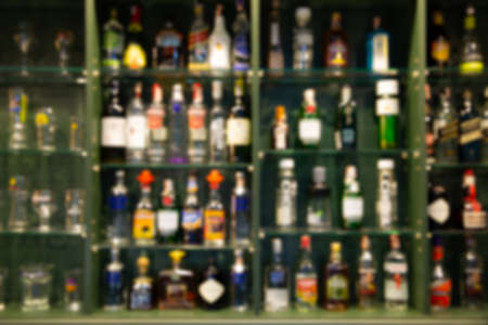 blur alcohol drink bottle on bar counter in the dark night background. for create Background or presentationの写真素材